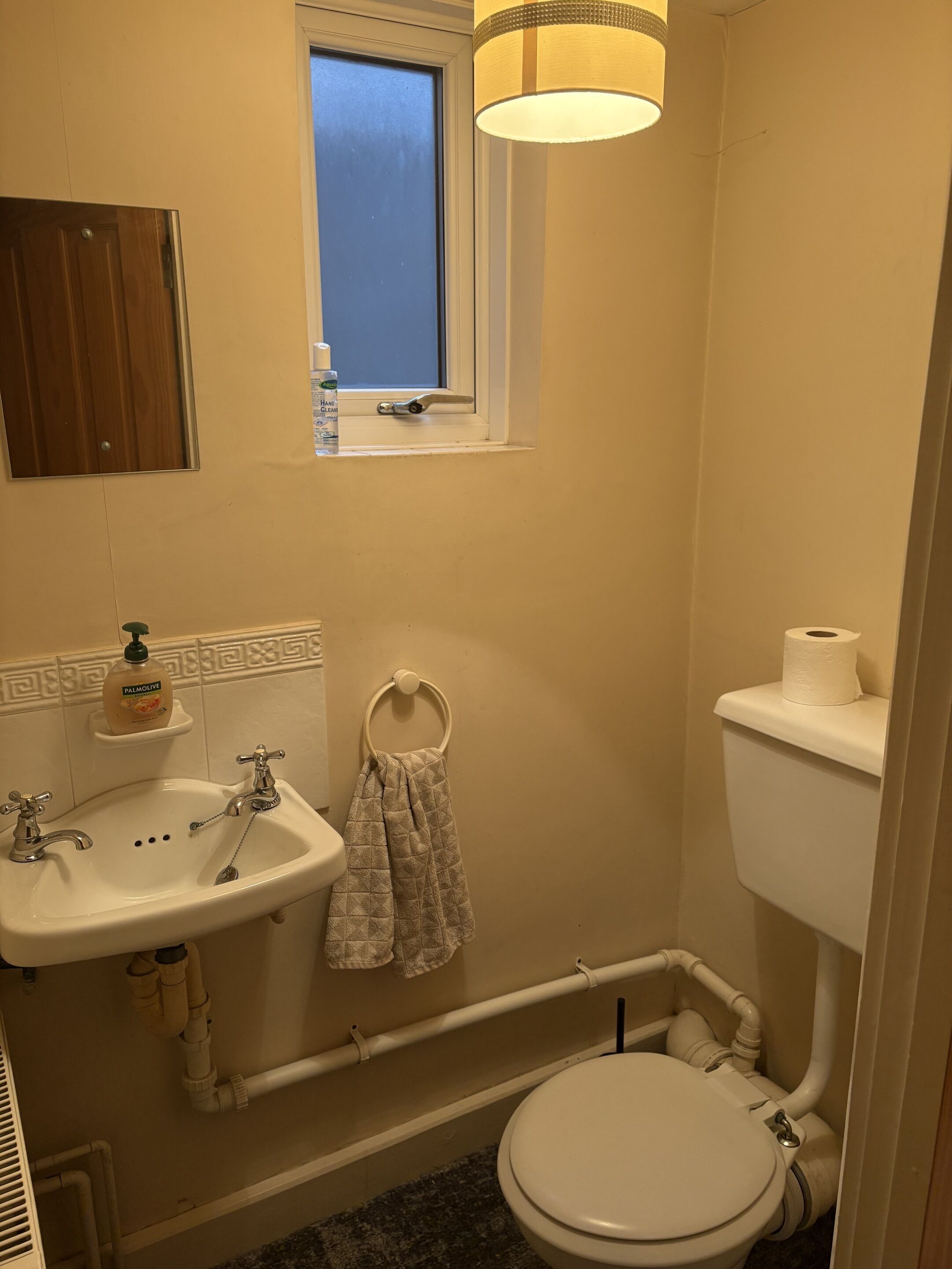 A small bathroom with a sink, toilet, and window.