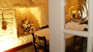 A room with a stone wall, a round table, and a mirror with a decorative frame. - Shawlee Cottage (Airdrie)