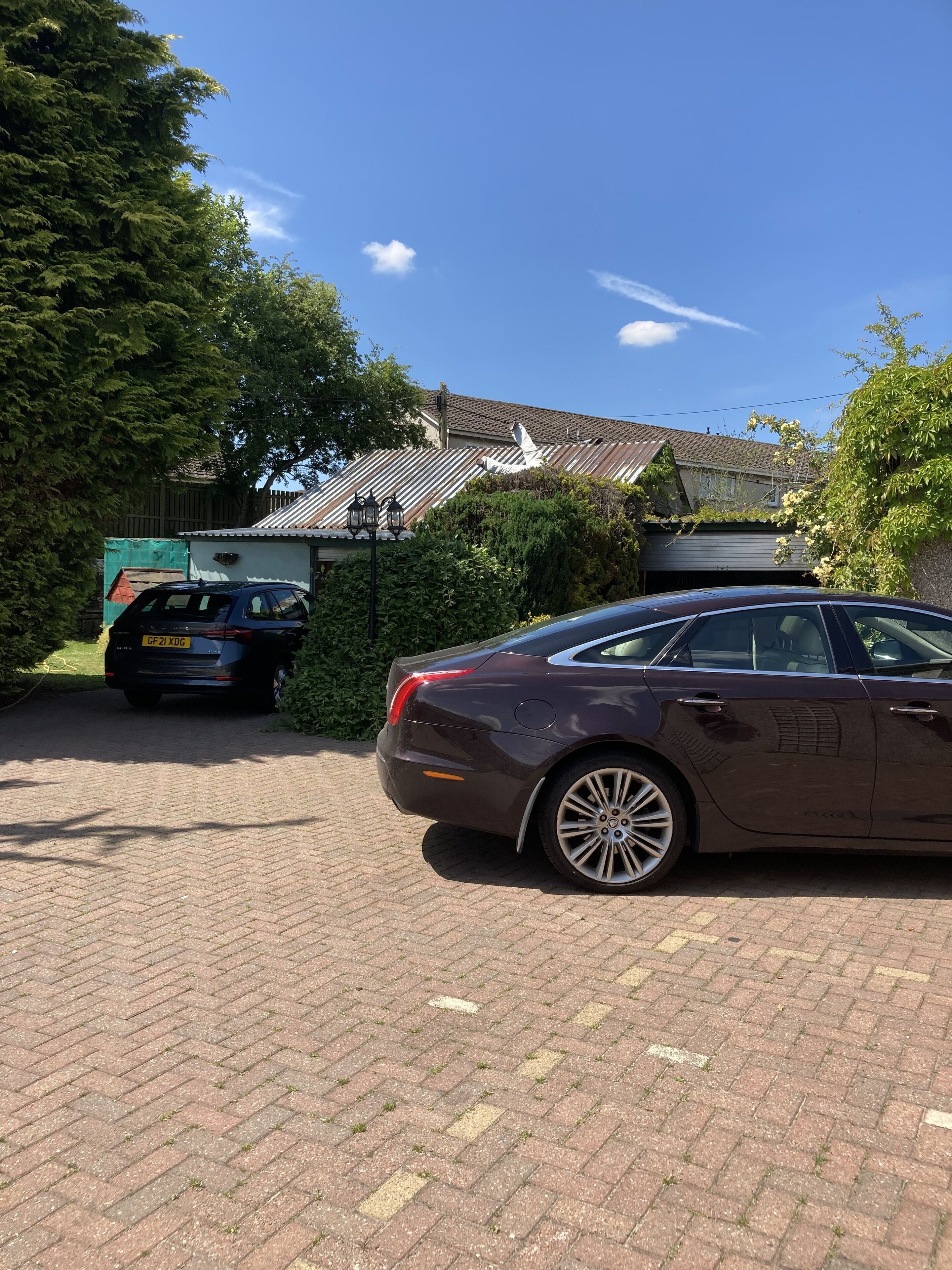 A parked car in a driveway with a house in the background.