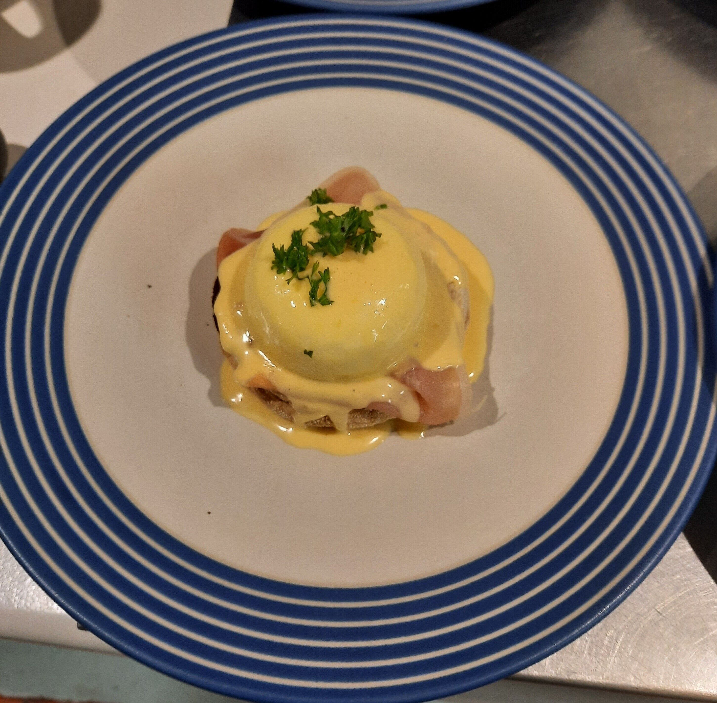 A plate with a dish that includes a poached egg, ham, and a creamy sauce, garnished with parsley.