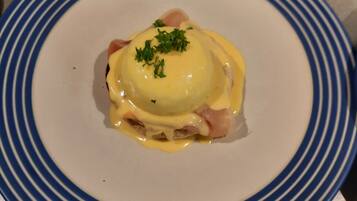 A plate with a dish that includes a poached egg, ham, and a creamy sauce, garnished with parsley.