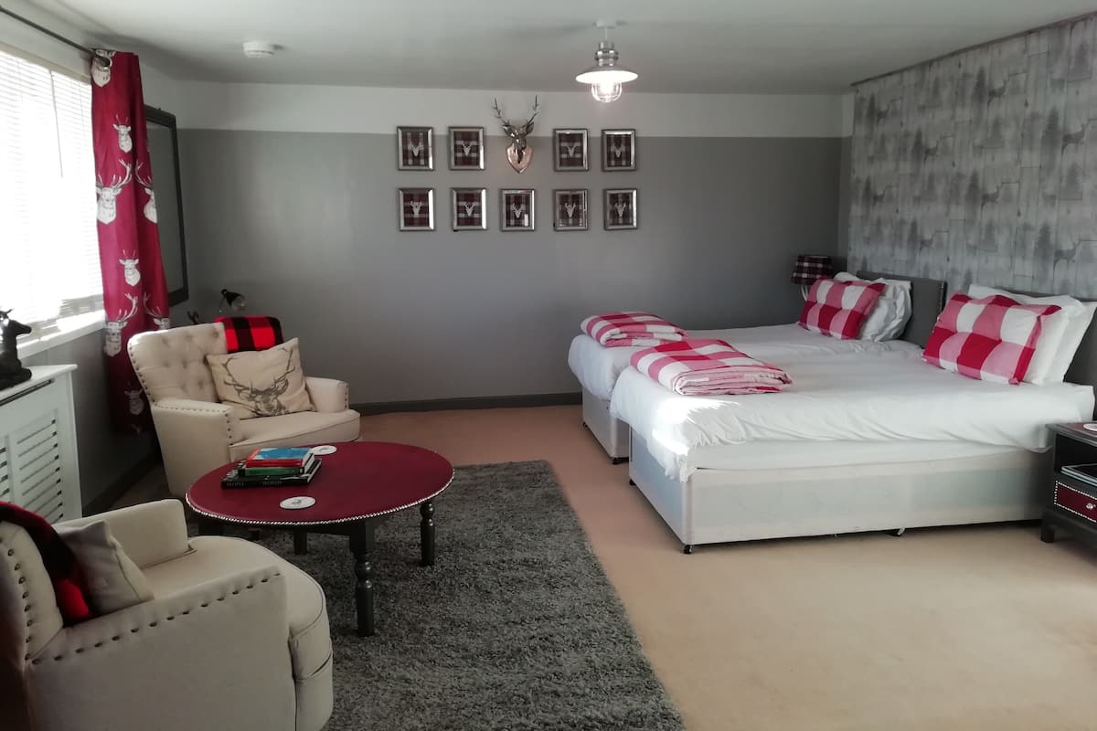 Quarto com uma cama grande, um sofá, uma pequena mesa e um ventilador de teto.