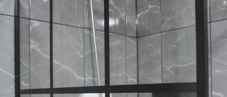 A modern shower enclosure with a handheld showerhead and a wall-mounted rain showerhead.