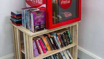 Una pequeña estantería de madera con varios libros y un refrigerador rojo de Coca-Cola.