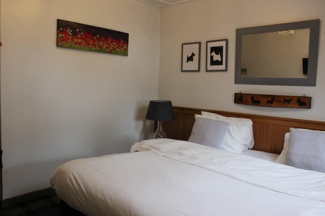 A hotel room with a bed, a lamp, a painting, and a mirror.