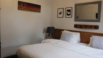 A hotel room with a bed, a lamp, a painting, and a mirror.