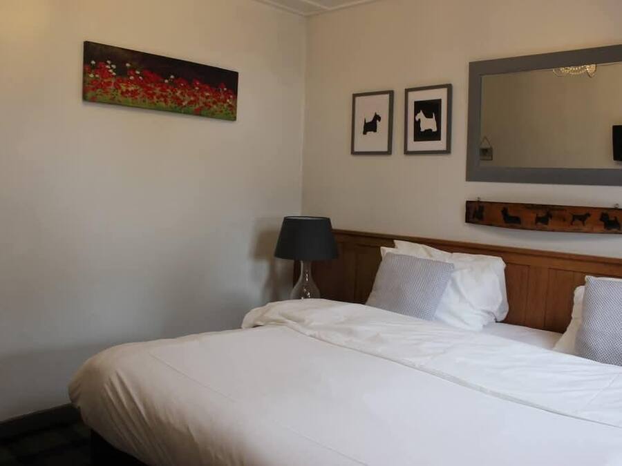 A hotel room with a bed, a lamp, a painting, and a mirror.