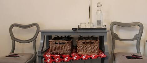 Una habitación con dos sillas, una mesa con cestas, una botella y un mantel rojo estampado.