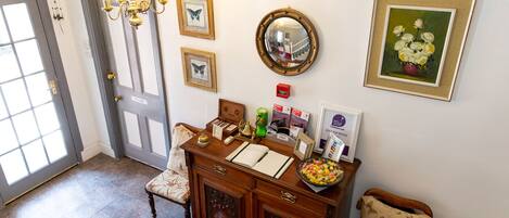 A foyer with a wooden bench, a mirror, framed artwork, and a chandelier.