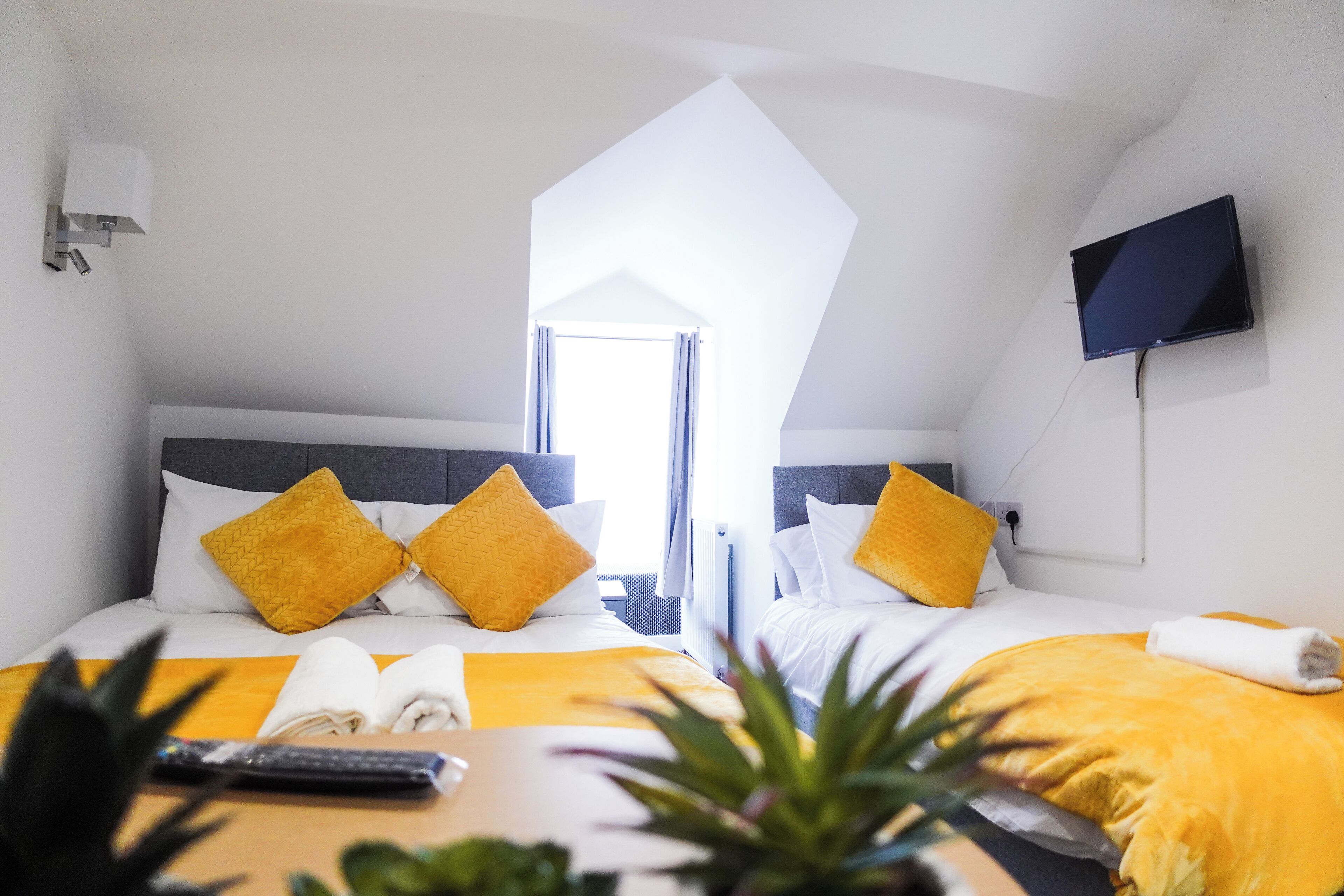 A hotel room with two beds, a TV, and a window.