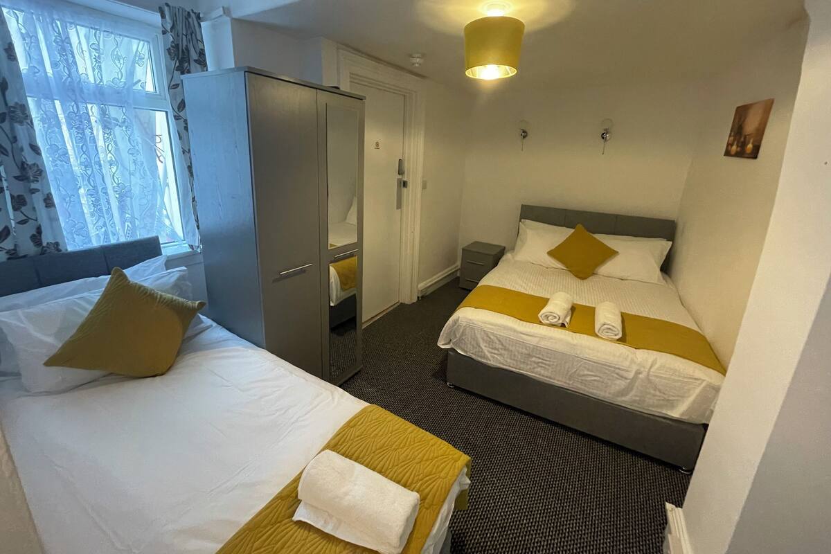 Et hotelværelse med to senge, et skab, et spejl og en loftlampe.