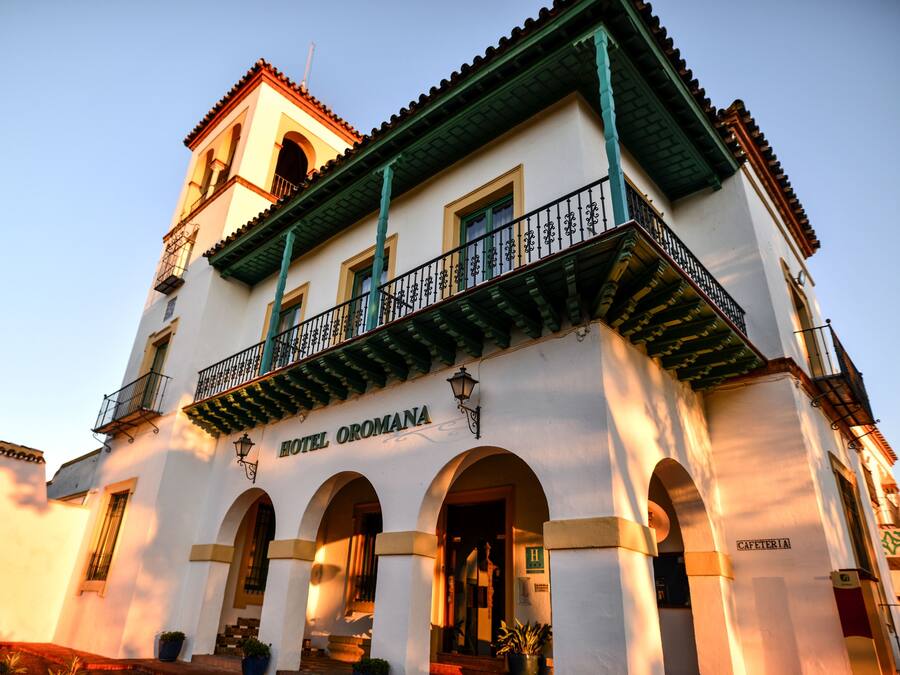 Un edificio de dos pisos con un balcón, ventanas de arco y un letrero que dice "HOTEL OROMANA".