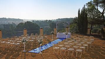 An outdoor wedding setup with rows of chairs and a blue aisle.