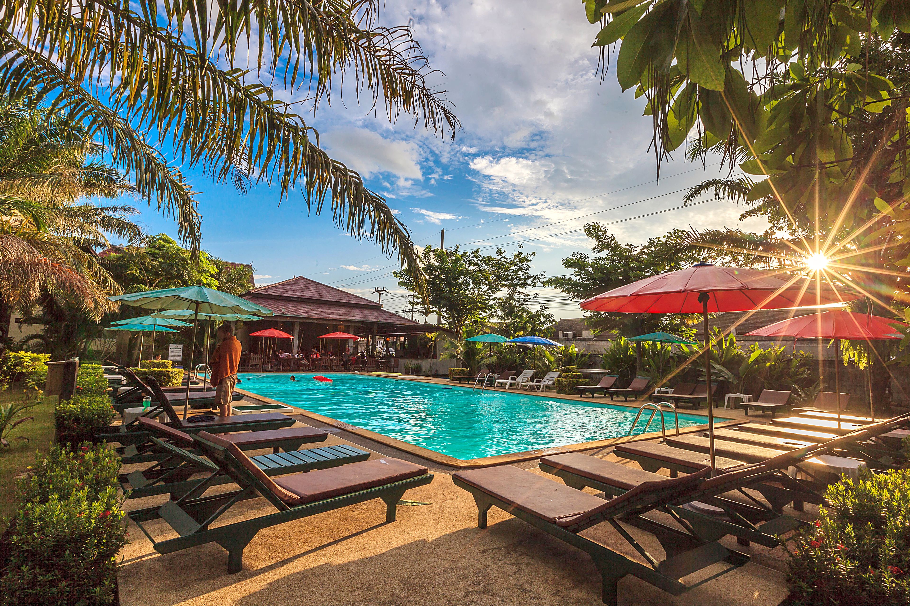 A pool area with lounge chairs and umbrellas, surrounded by greenery.