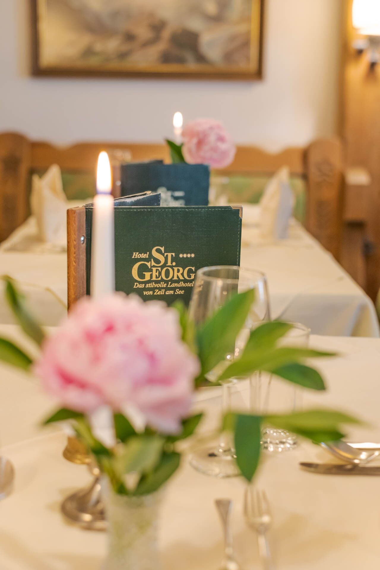 Una mesa dispuesta con una vela, un menú y un florero con flores.