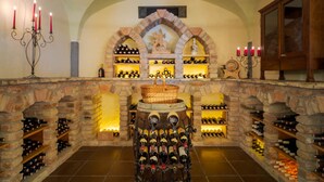 Una bodega con paredes de piedra, estanterías para vino y una barrica central.