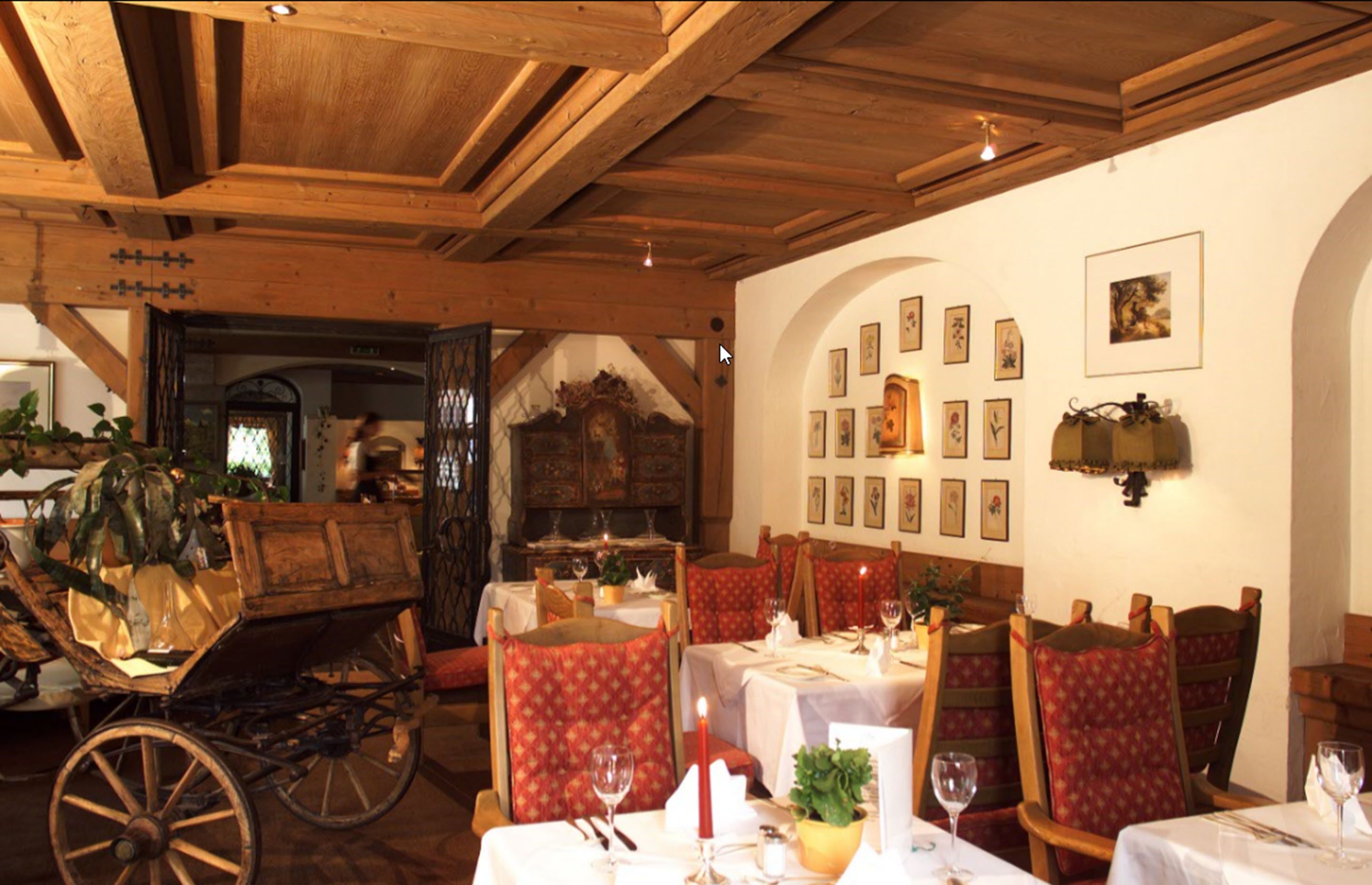 Un restaurante con vigas de madera, sillas tapizadas en rojo y manteles blancos.
