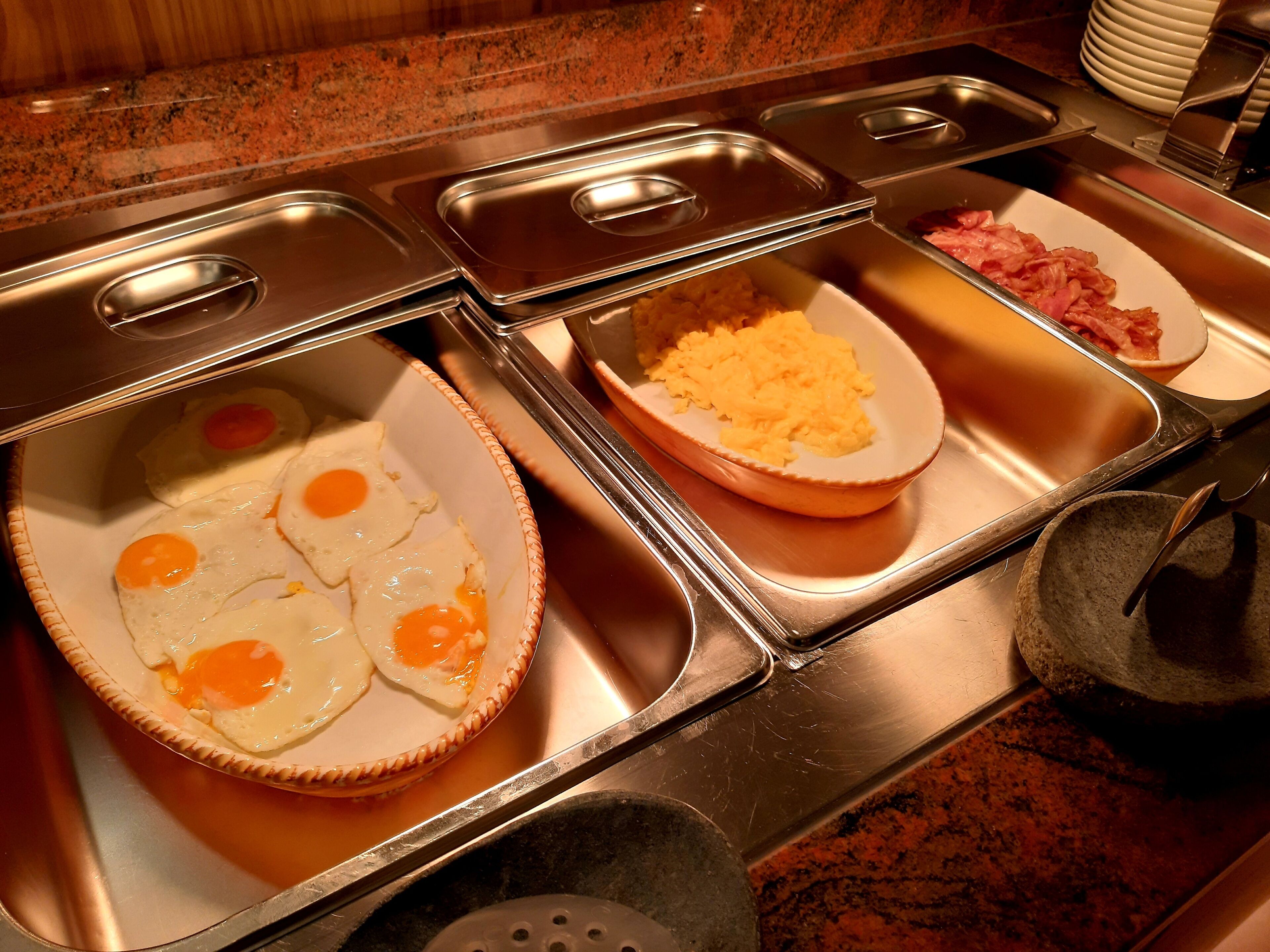 Een buffetopstelling met diverse soorten eten, waaronder eieren en roerei.