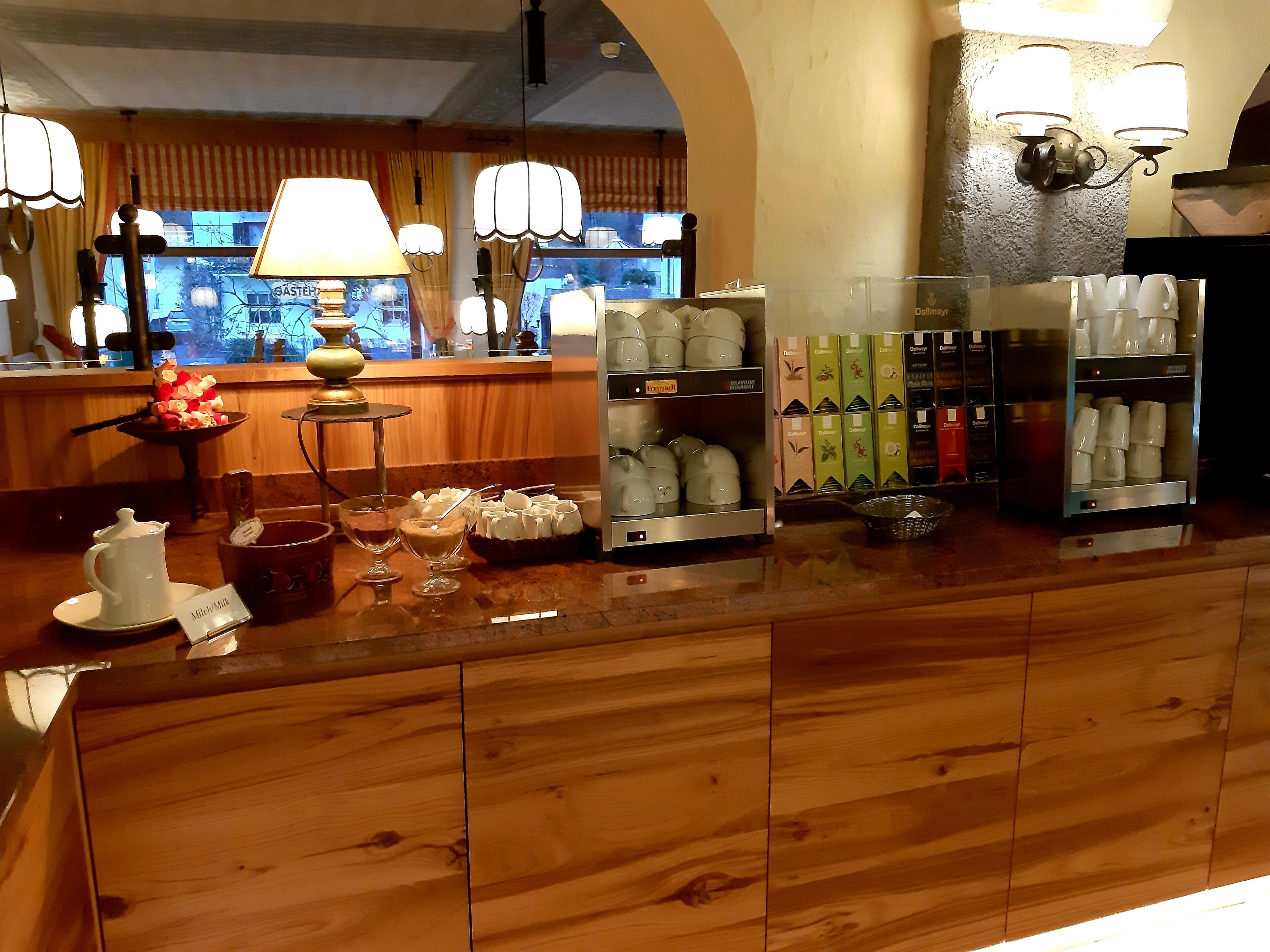 Ein Hotel-Empfangsbereich mit Holztresen, einer Kaffeemaschine und einer Auswahl an Tee-Kartons.