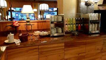 Ein Hotel-Empfangsbereich mit Holztresen, einer Kaffeemaschine und einer Auswahl an Tee-Kartons.