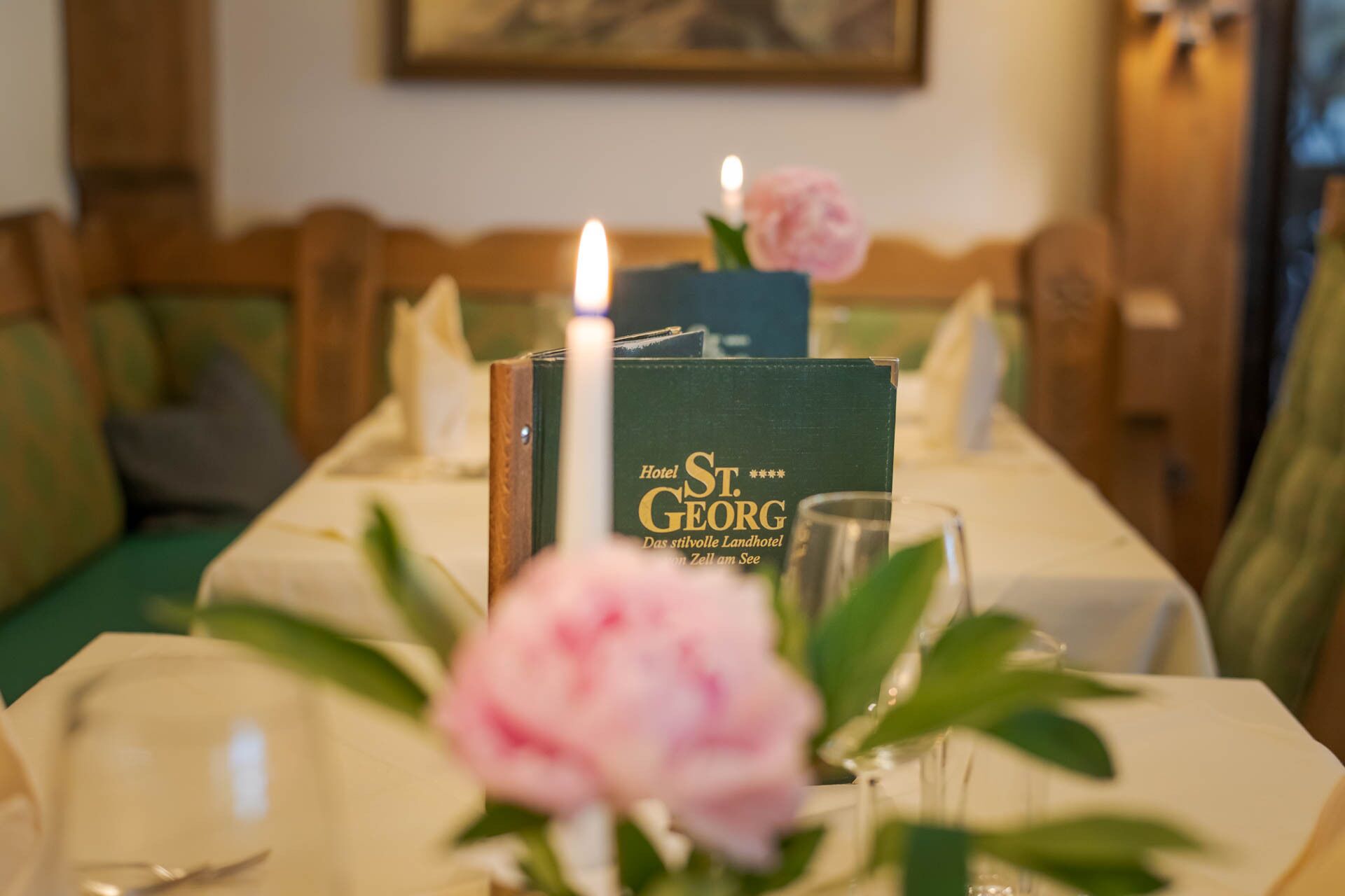 A table set with a candle, a glass, and a menu for Hotel St. Georg.