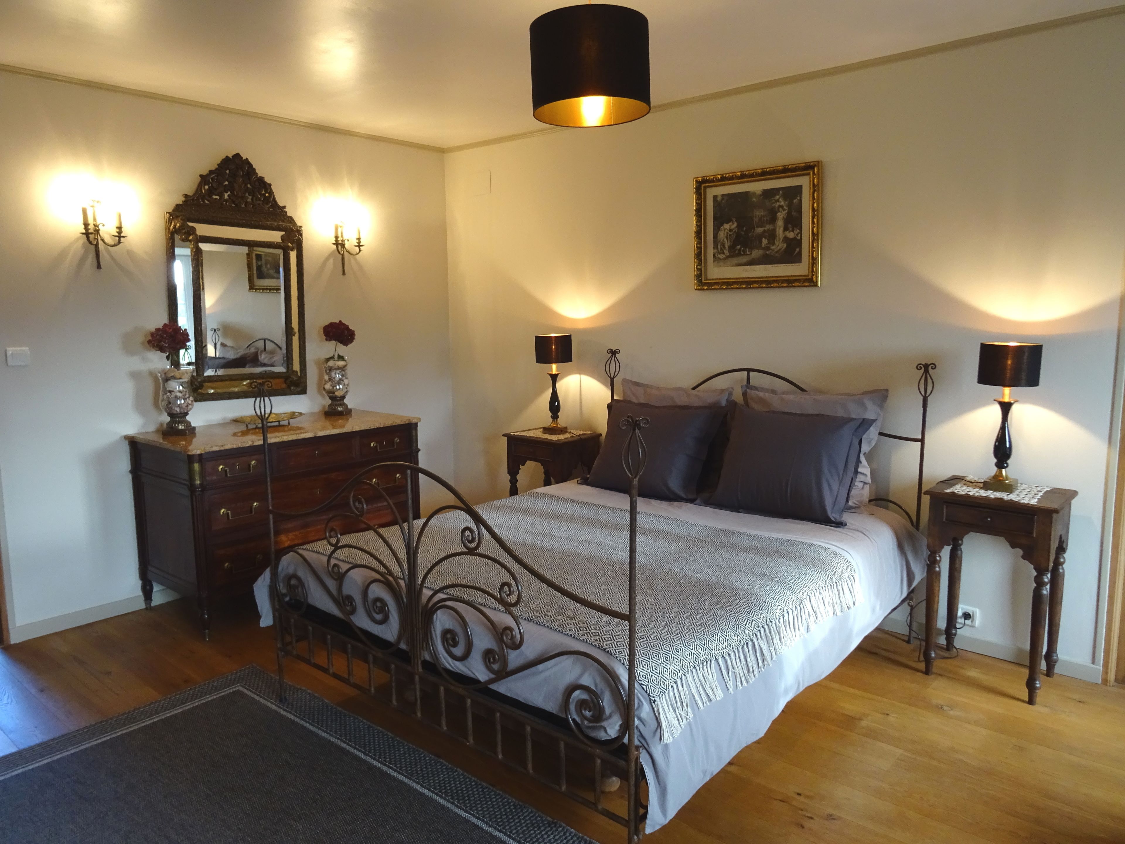 A bedroom with a bed, dresser, and two nightstands with lamps.