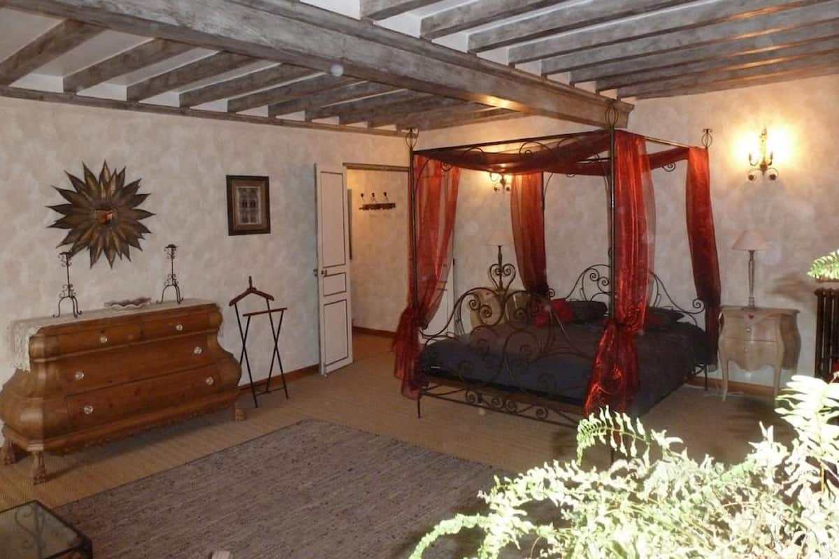 A bedroom with a four-poster bed, a wooden dresser, and a large star-shaped wall decoration.