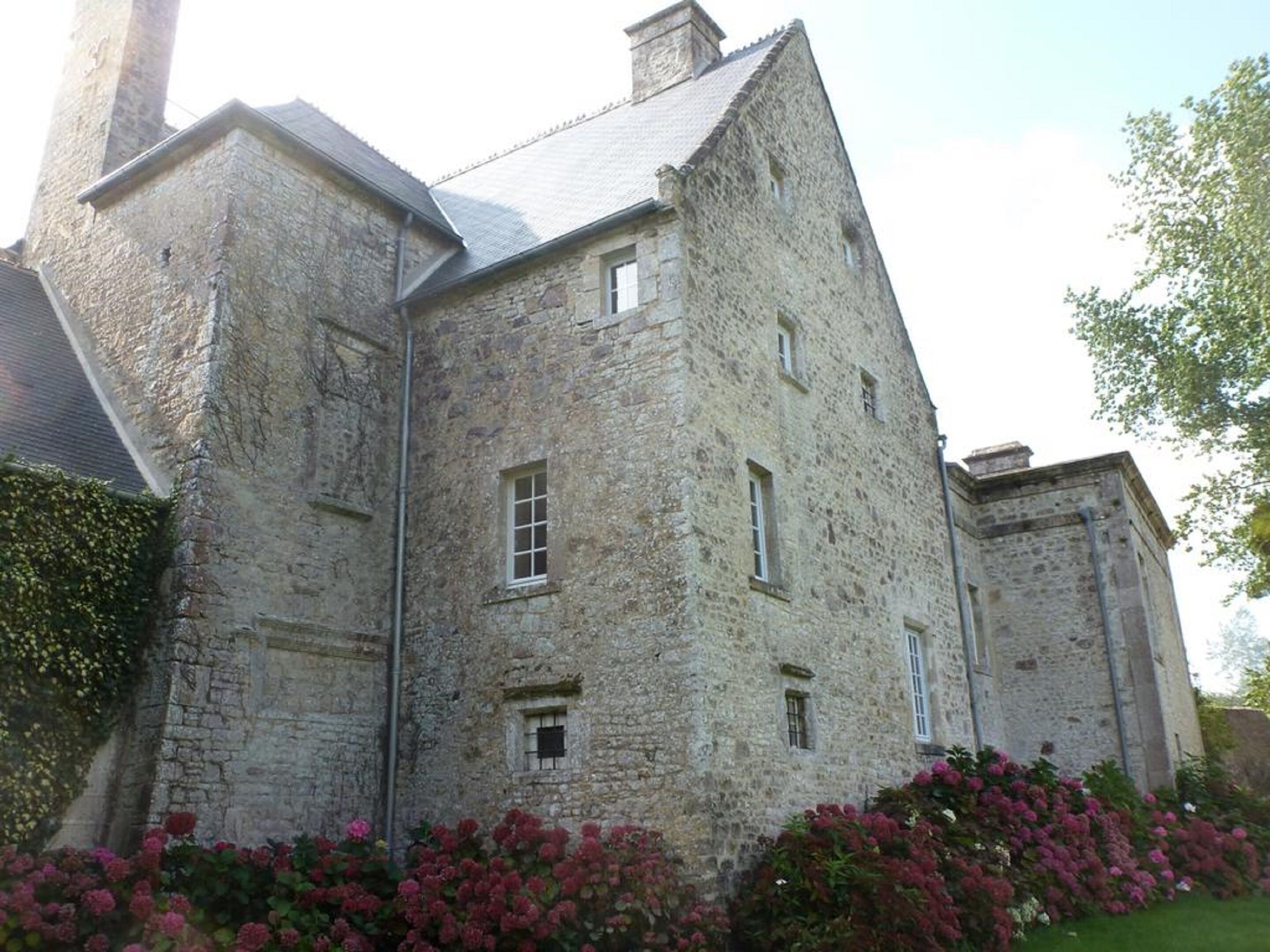 Un bâtiment en pierre doté de nombreuses fenêtres et d’une cheminée.