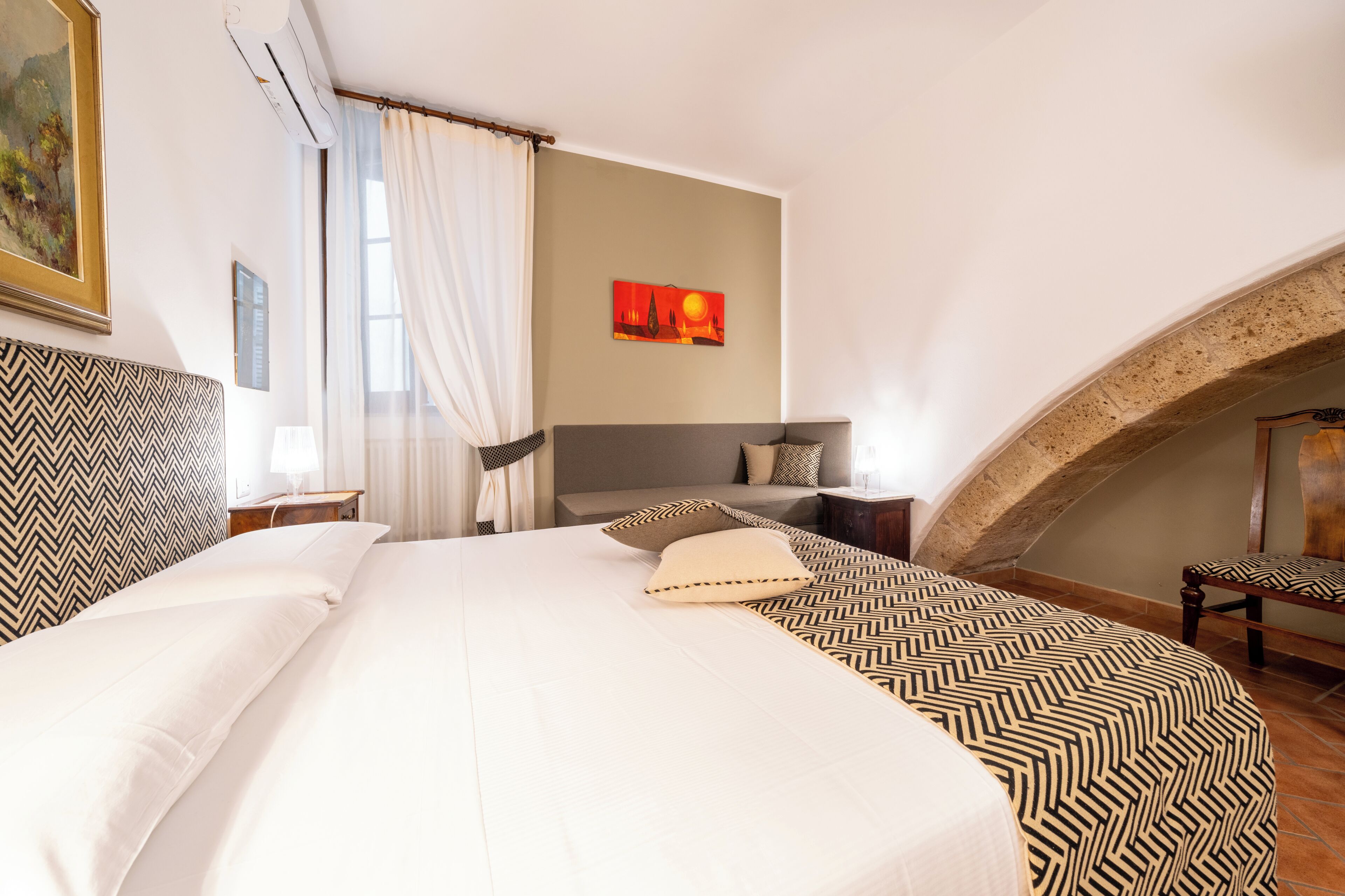 Une chambre d’hôtel avec un grand lit, un bureau, une chaise, un tableau et une vue sur le paysage urbain.