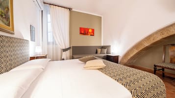 Ein Hotelzimmer mit einem großen Bett, einem Schreibtisch, einem Stuhl, einem Gemälde und Blick auf eine Stadtlandschaft.