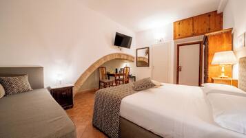 A hotel room with two beds, a TV, a wooden archway, a desk, and a mirror.