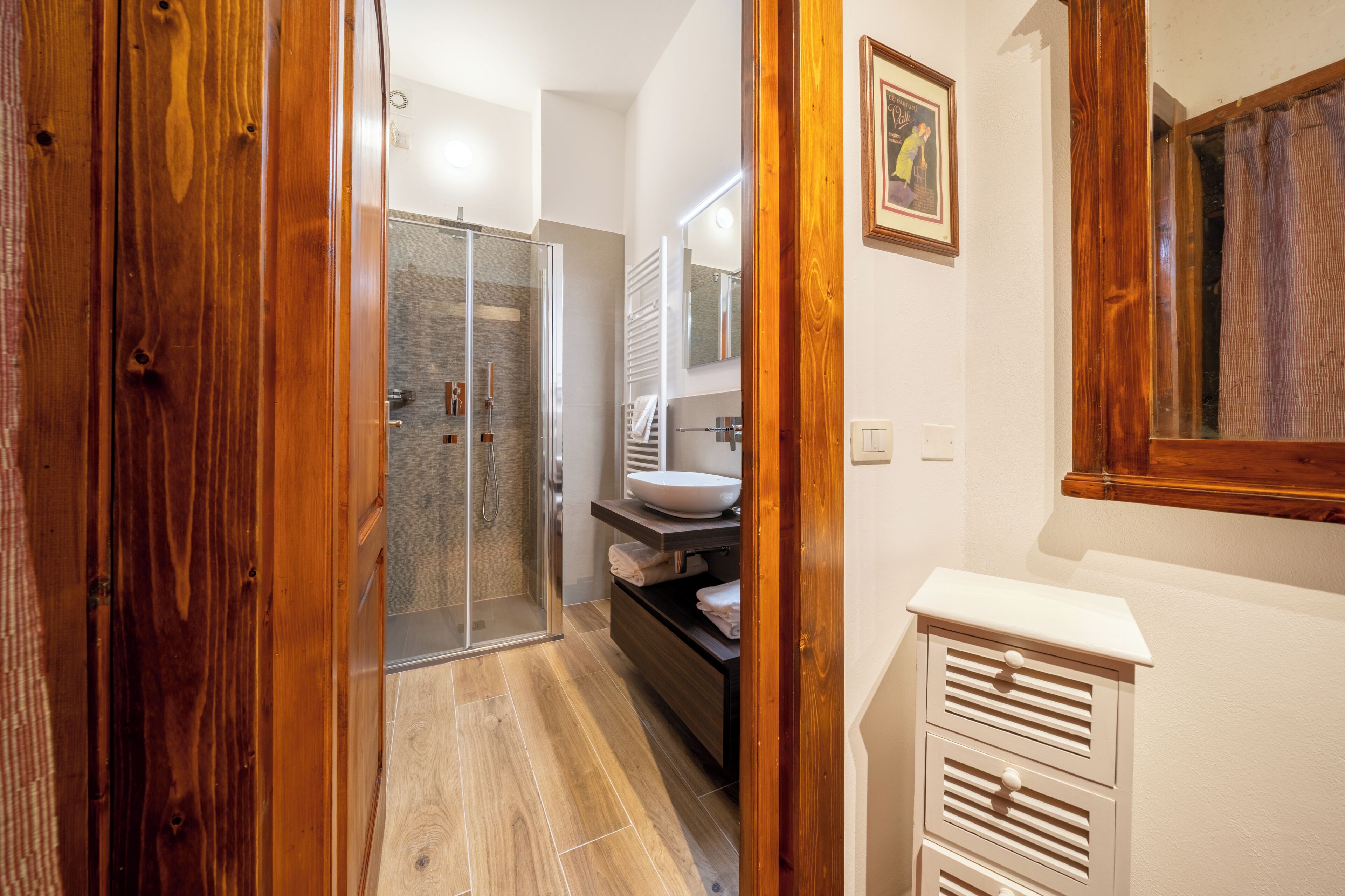 A bathroom with a glass shower, a white sink, and wooden doors.