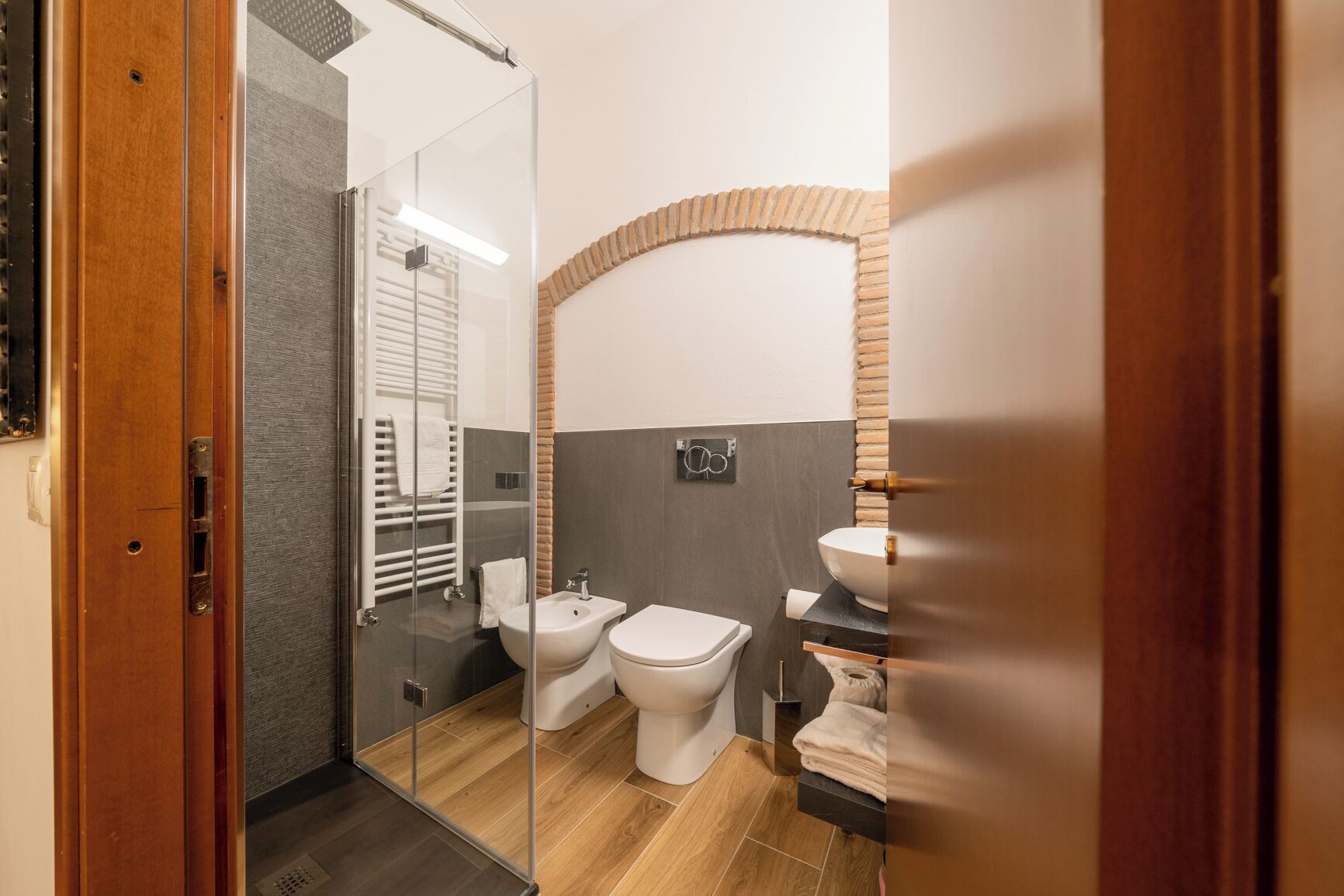 Un baño moderno con cabina de ducha de vidrio, un bidé, un inodoro y un lavabo.