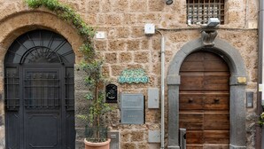 Un edificio de piedra con dos grandes puertas de madera, una planta en maceta y un letrero que dice