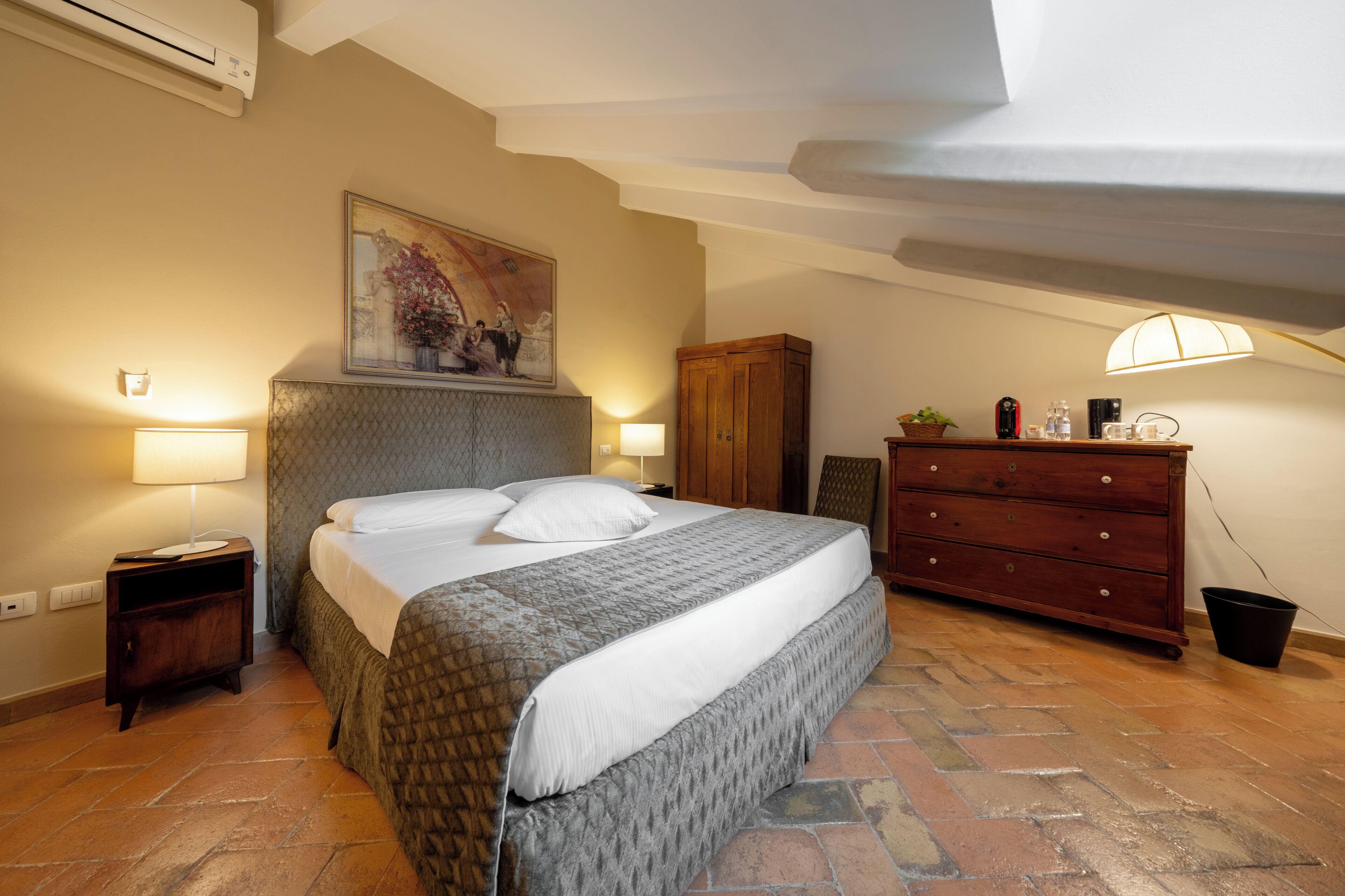 Un dormitorio con cama, mesitas de noche, cómoda y un cuadro en la pared.