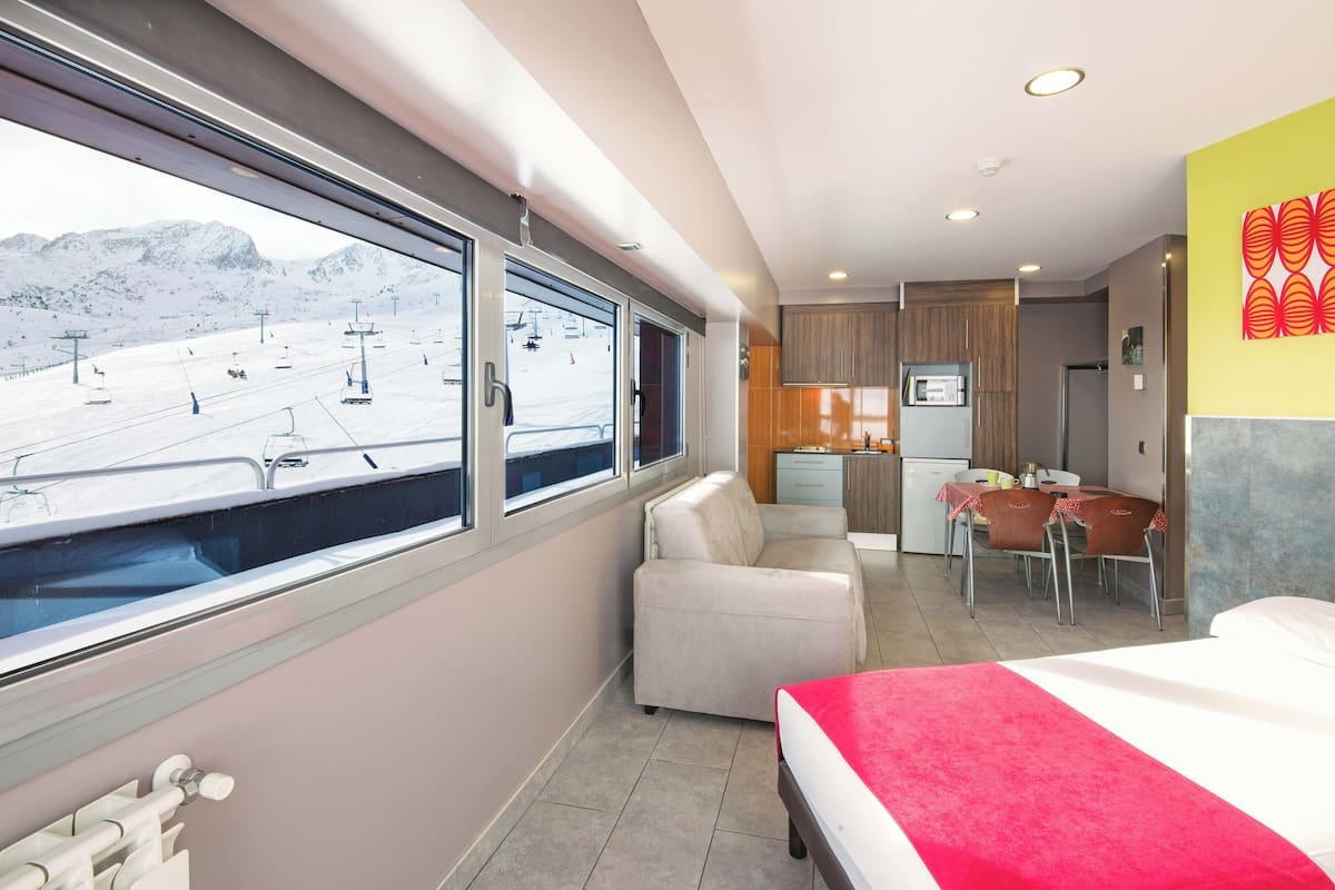 A hotel room with a bed, a sofa, a dining area, and a kitchen.