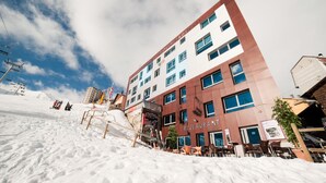 Un edificio de varios pisos con un restaurante en la planta baja, rodeado de nieve.