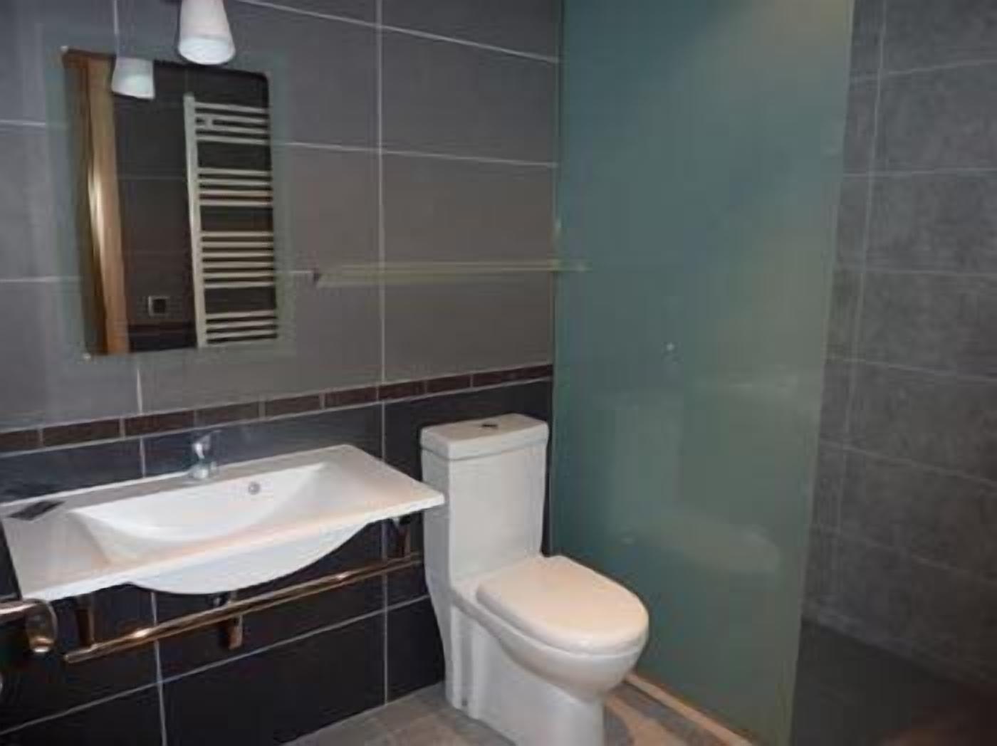 Une salle de bain moderne avec un lavabo blanc, des toilettes et une douche à parois de verre.