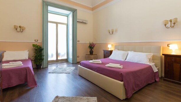 A hotel room with two beds, a large window, and a door leading outside. - Teatro Bellini - Bed & Breakfast (Catania)
