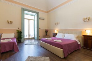 Quarto de hotel com duas camas, uma janela grande e porta que dá para o exterior.