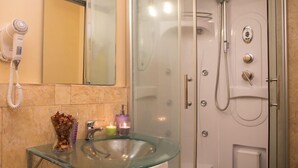 A bathroom with a glass sink, a hairdryer, and a shower with a glass door. - Teatro Bellini - Bed & Breakfast (Catania)