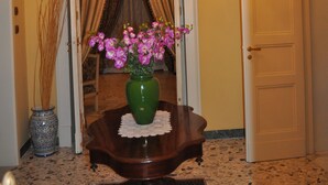 A hallway with a chandelier, a vase with flowers, and a door. - Teatro Bellini - Bed & Breakfast (Catania)