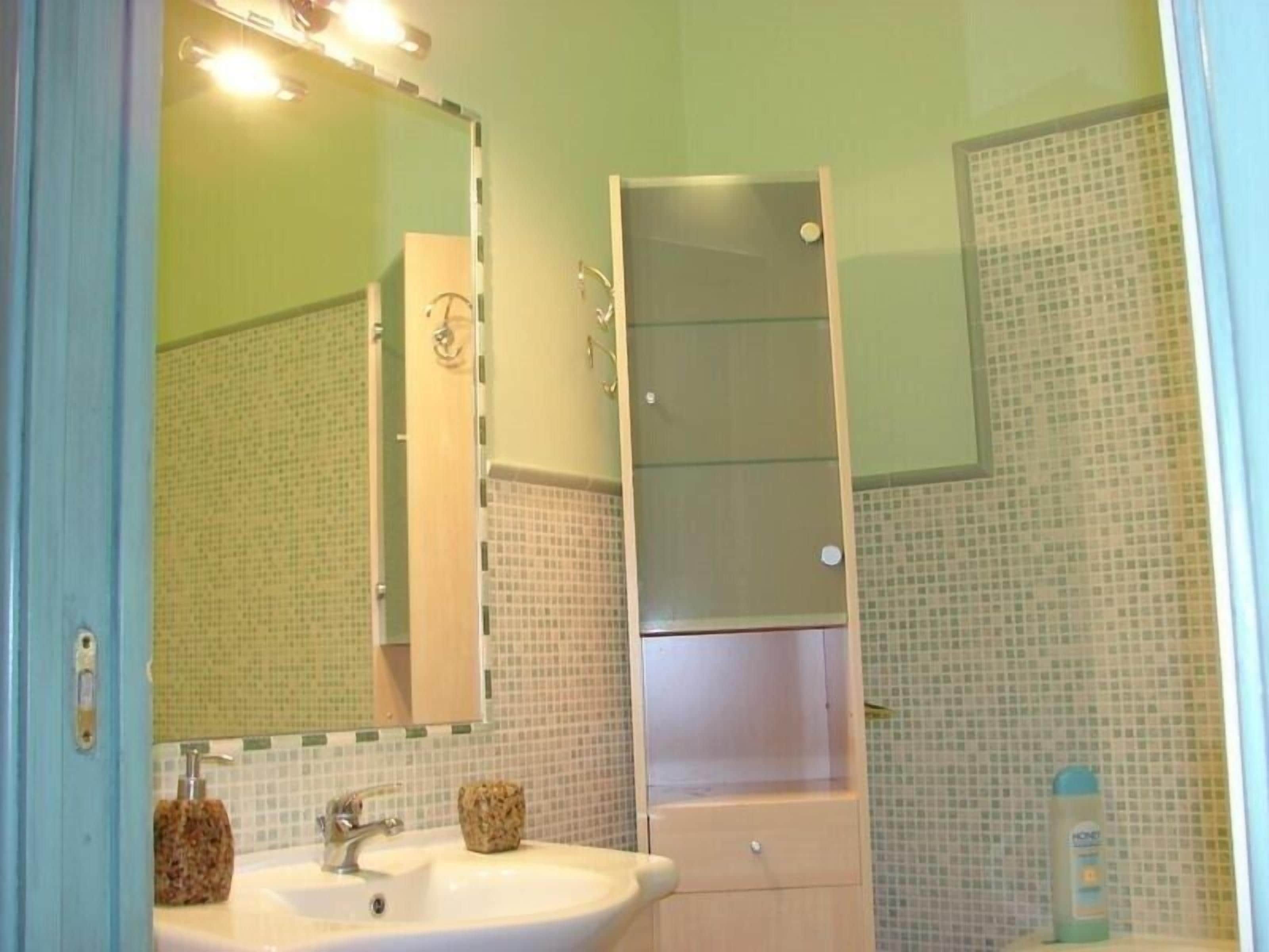 A bathroom with a sink, mirror, and shower.