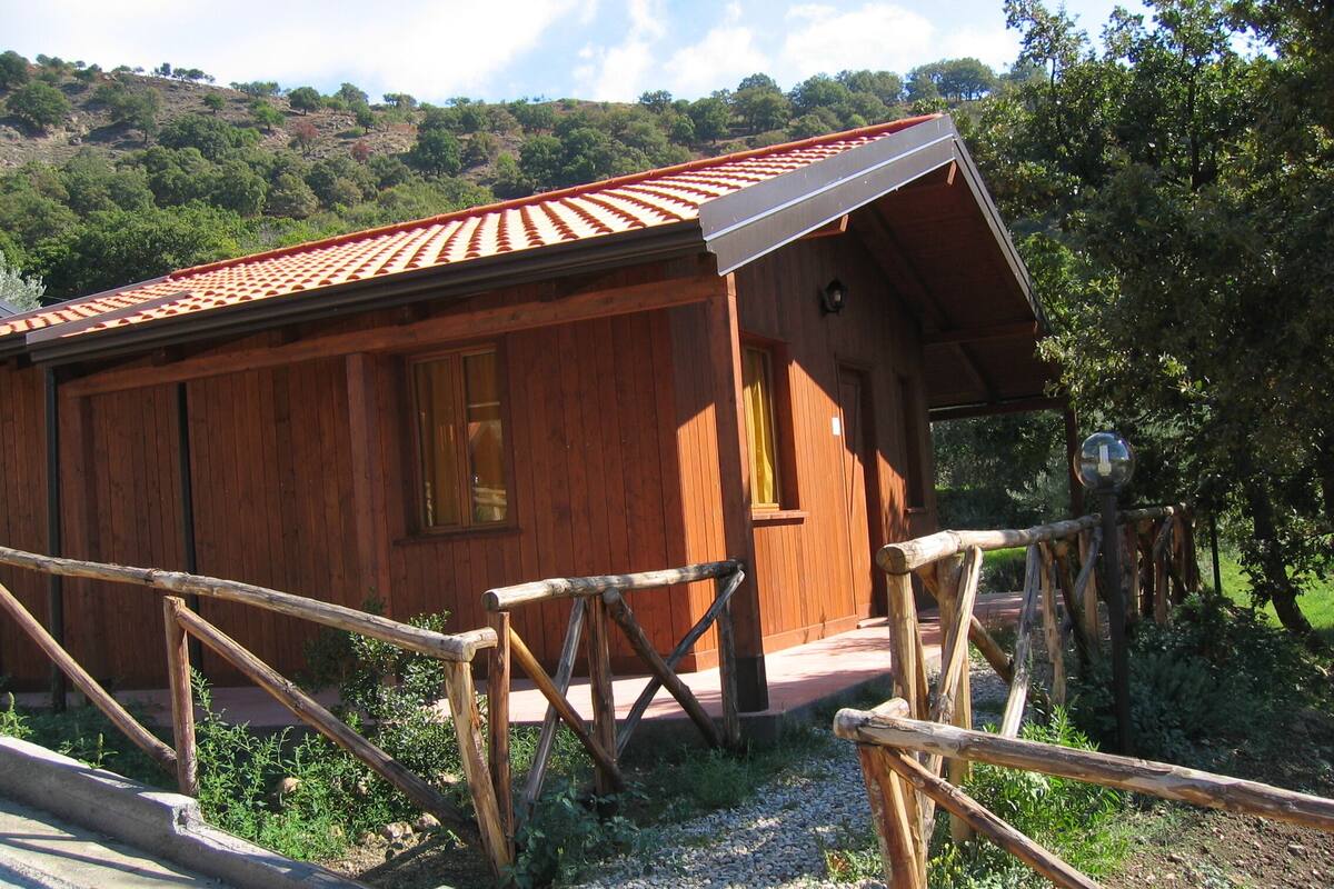 Eine Holzhütte mit geneigtem Dach, einer Veranda und einem Holzzaun.