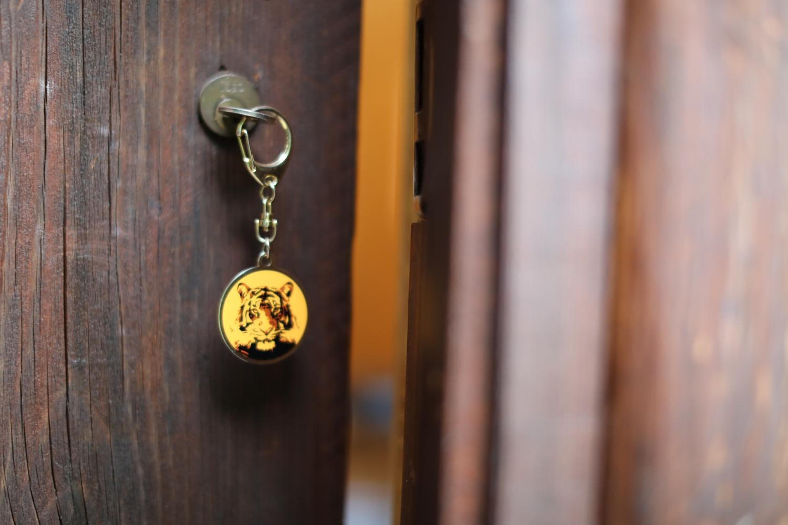 Une porte avec une poignée de porte en laiton et un porte-clés orné d’un tigre.