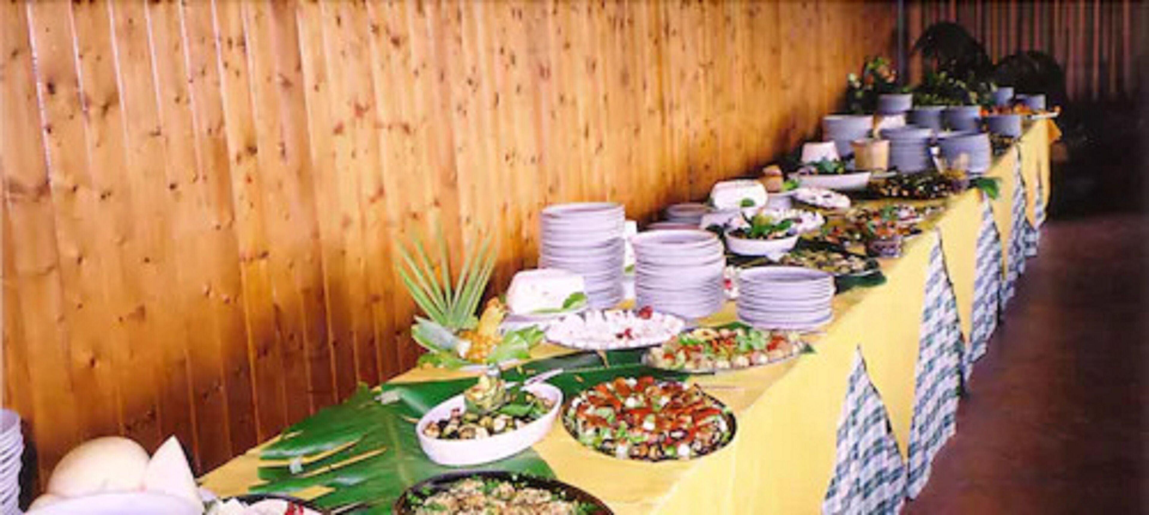A buffet table with various dishes and a yellow tablecloth.