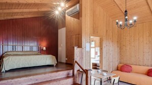 Ein Holzinnenraum mit einem Bett, einem Tisch mit Stühlen und einem Sofa.