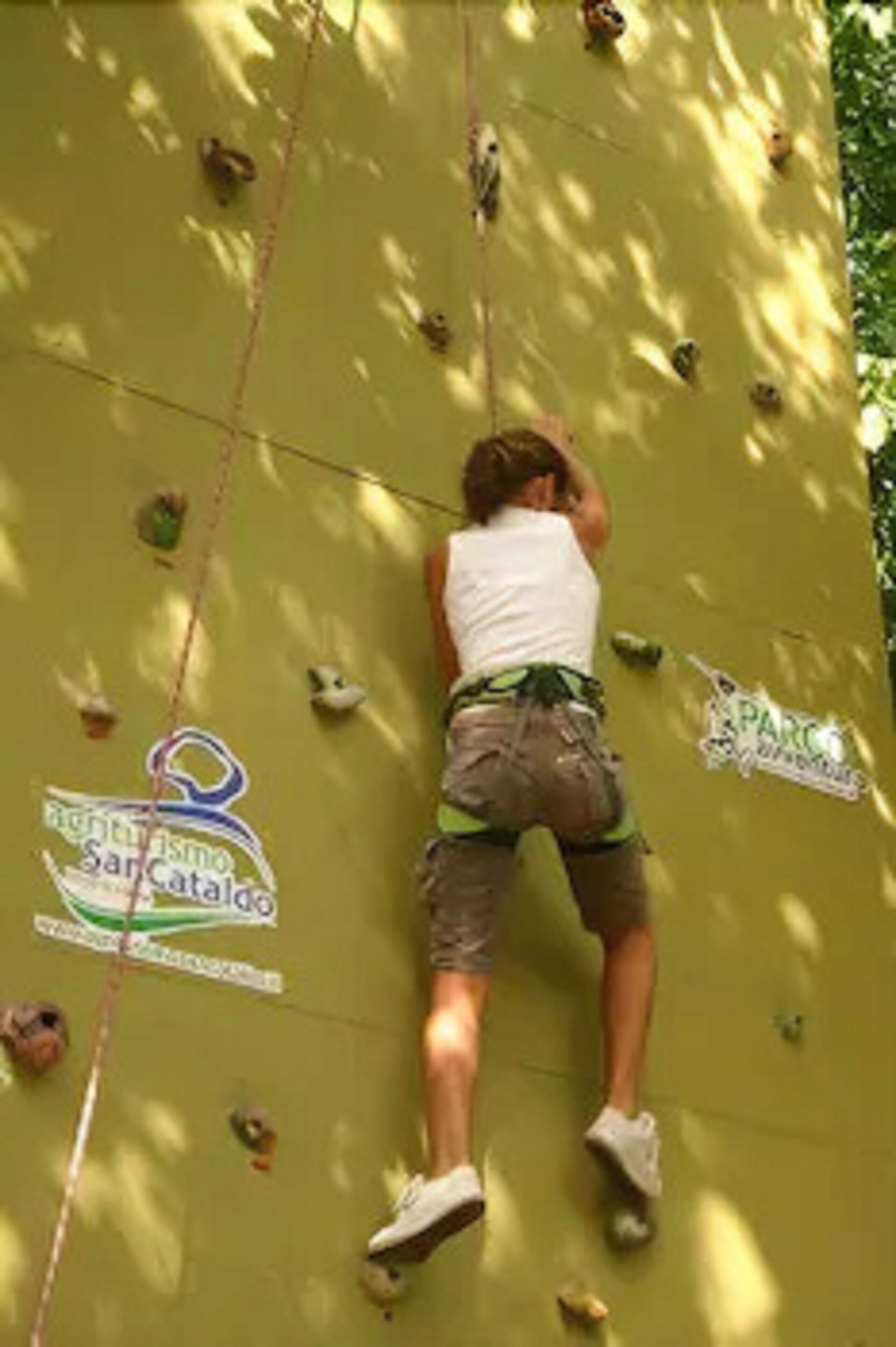 A person climbing a wall with handholds and a logo that reads "Right Tourism San Cataldo".