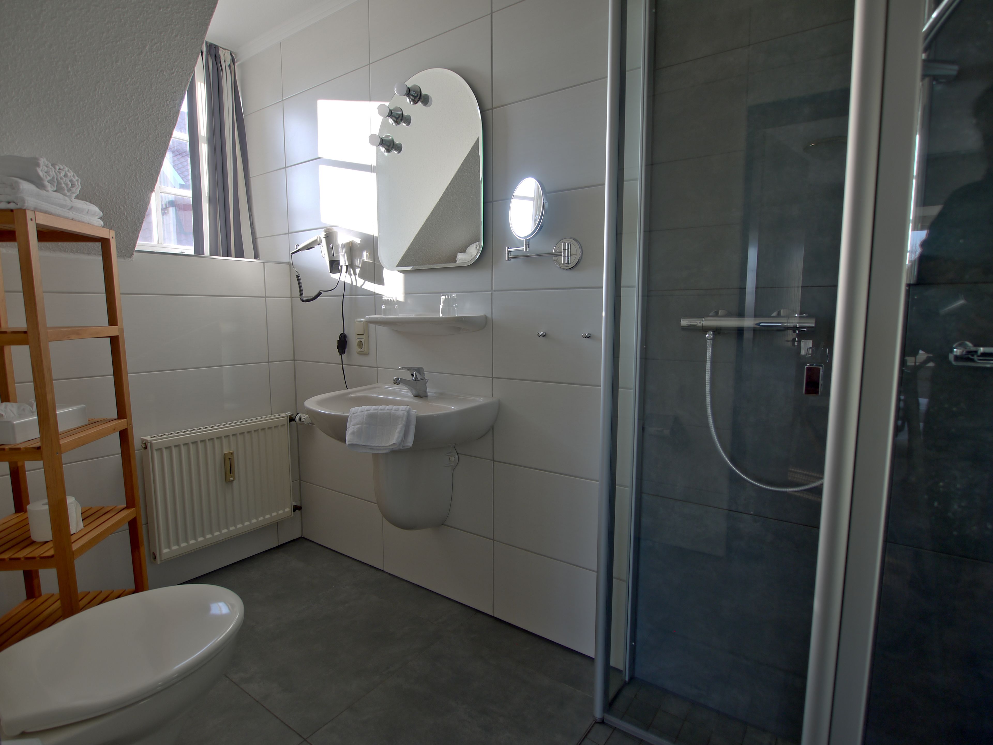 A bathroom with a toilet, sink, shower, and a mirror.