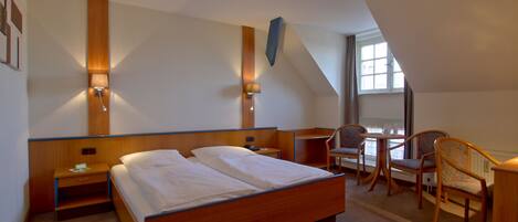 A hotel room with a large bed, bedside tables, a desk, and a chair.